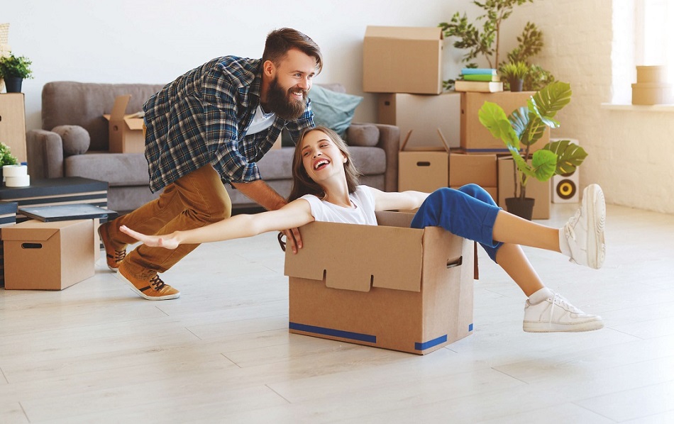 Mann schiebt Freundin im Karton durchs Wohnzimmer